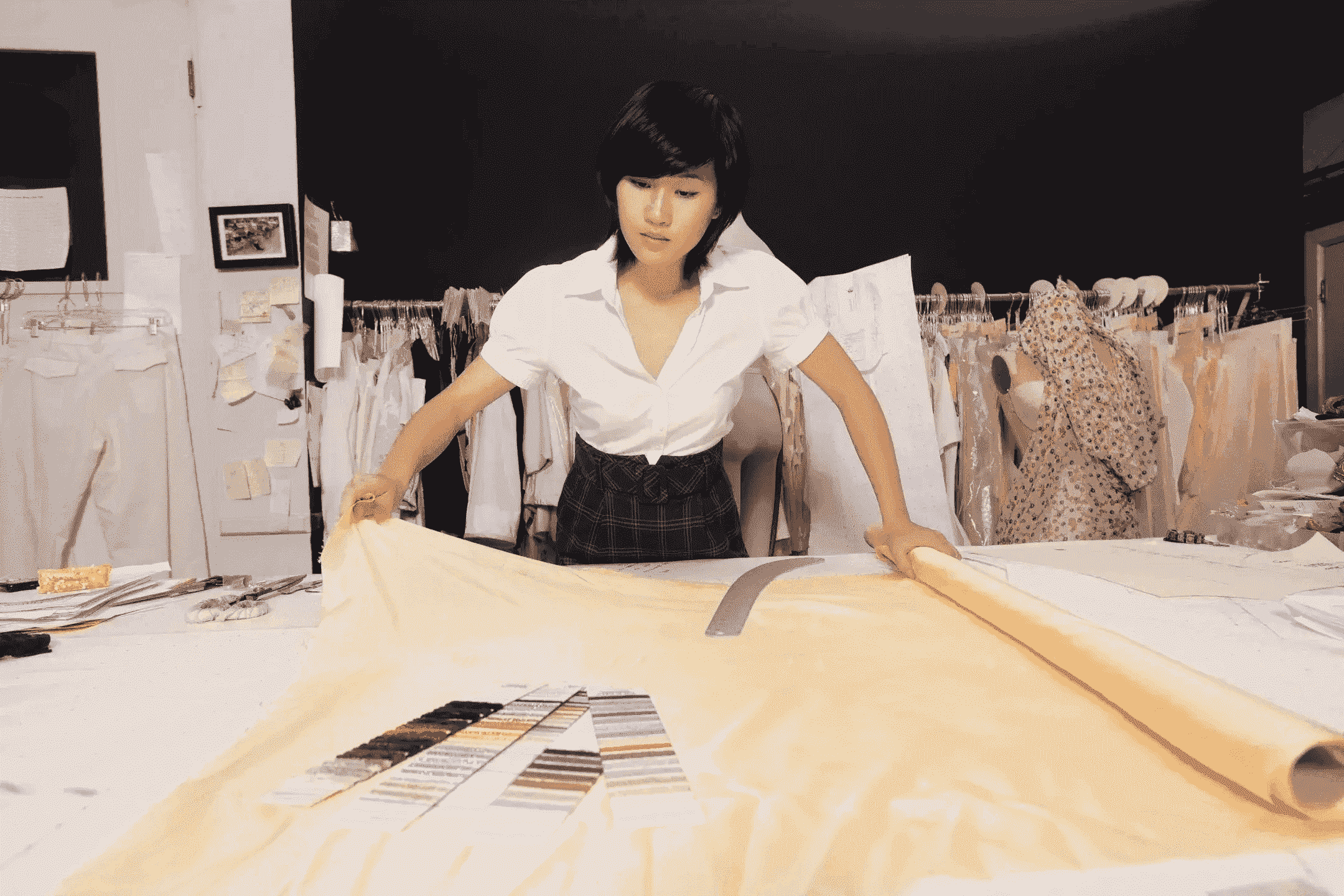 A woman standing over a table with papers on it.