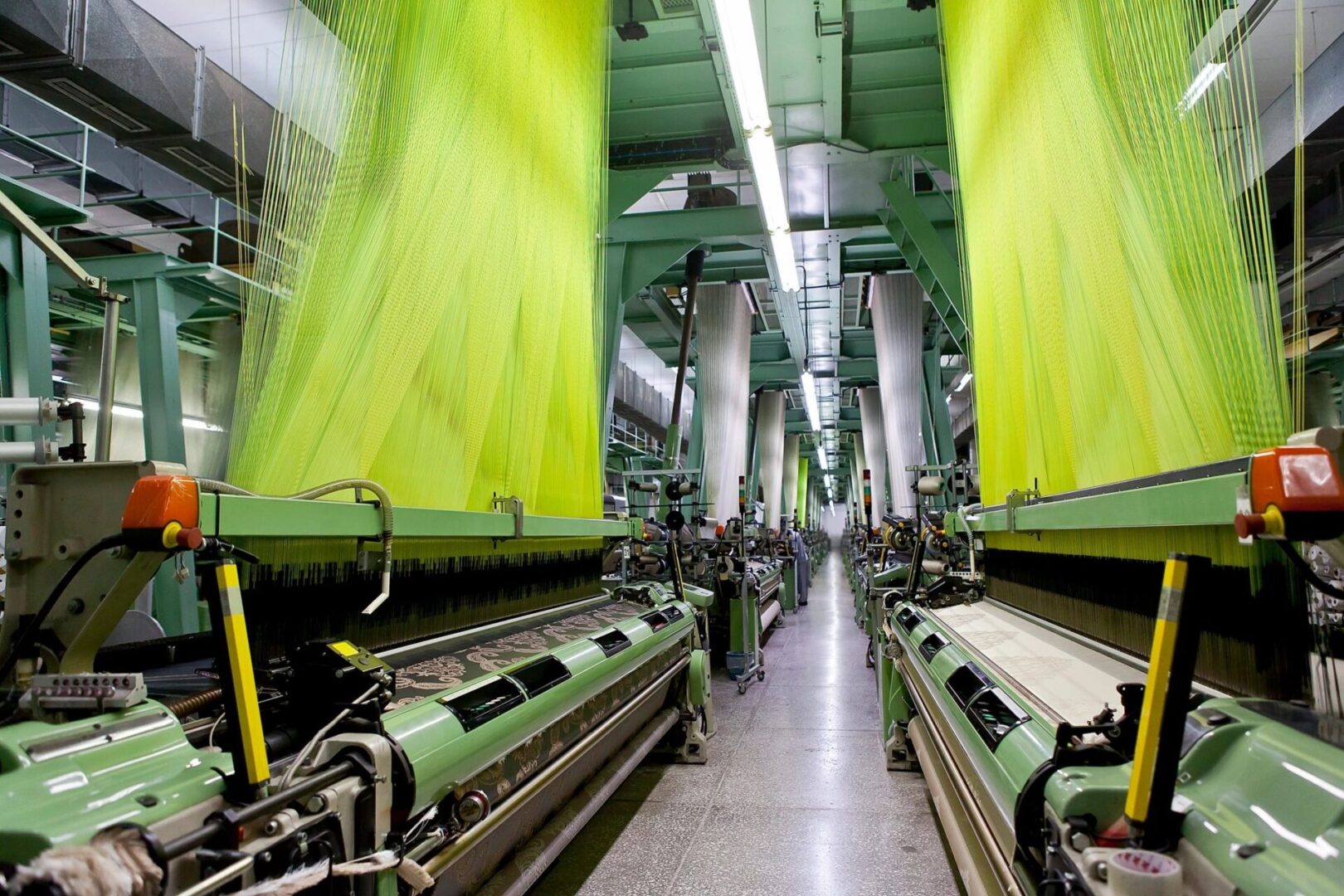 A large green machine in a factory with many green curtains.